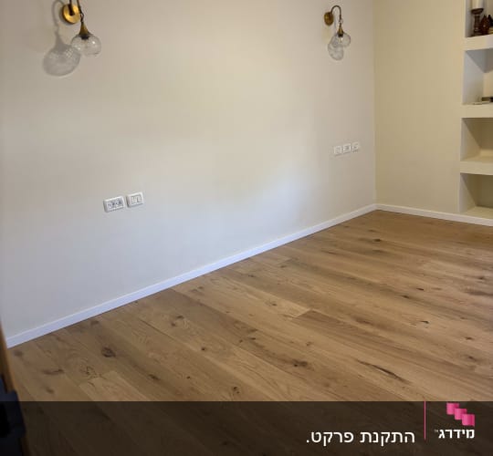 רצפת פרקט עץ בחדר עם קירות בהירים ותאורה קיר.